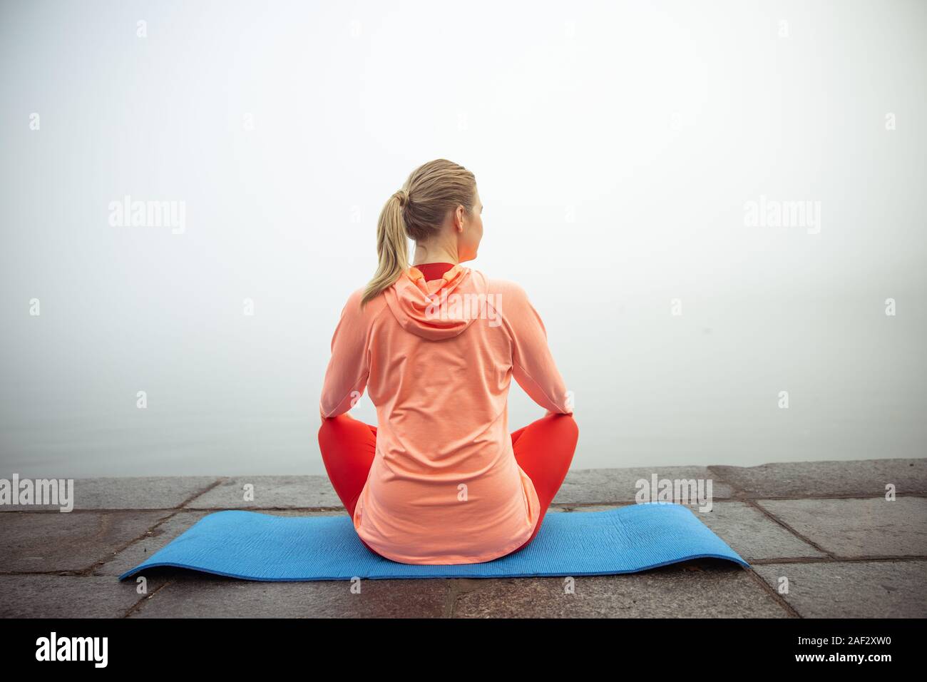 Young woman sitting on yoga mat outdoors Stock Photo - Alamy