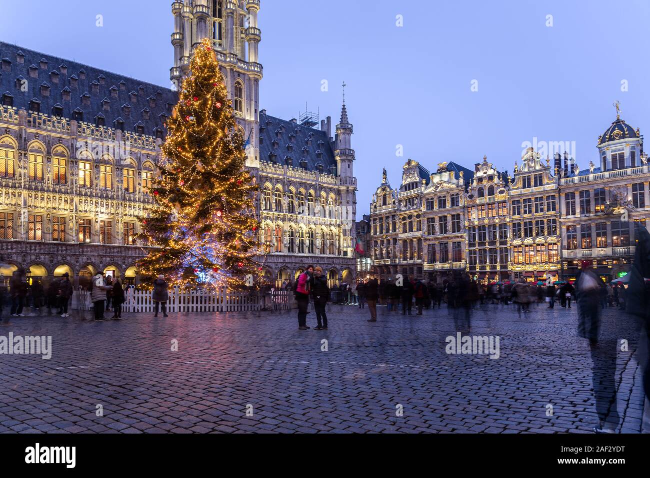 People wandering around the beautiful historic Grand Place decorated and illuminated for Christmas in Brussels old town on a winter night Stock Photo