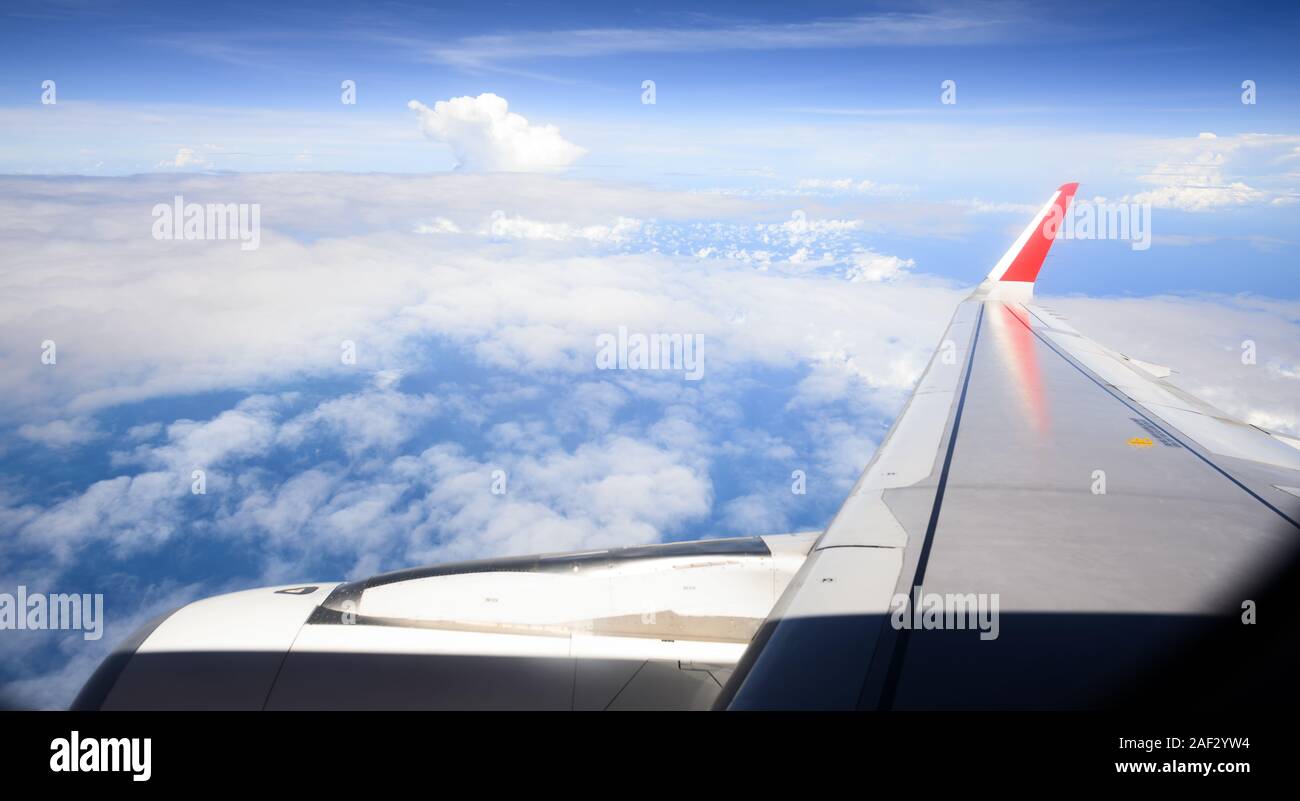 (Selective focus) Stunning view through the window of an airplane flying over some beautiful fluffy clouds. Stock Photo