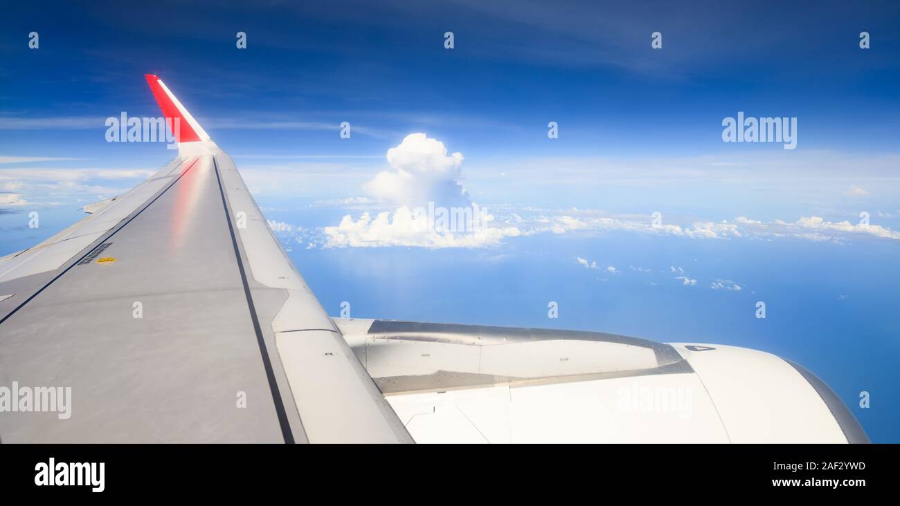 (Selective focus) Stunning view through the window of an airplane flying over some beautiful fluffy clouds. Stock Photo