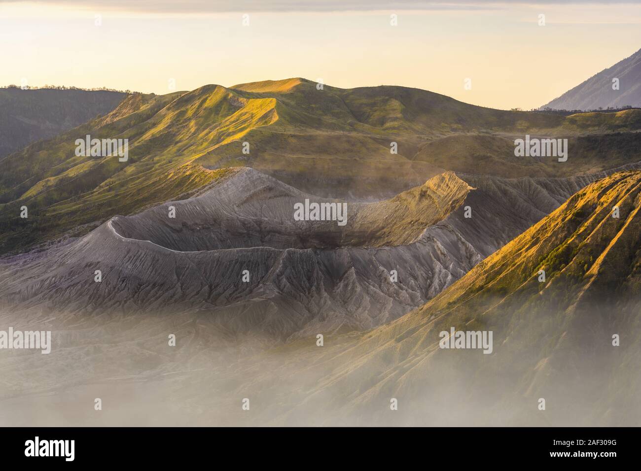 View from above, stunning close-up view of the Mount bromo crater and the Mount Batok surrounded by clouds during a beautiful sunrise. Stock Photo
