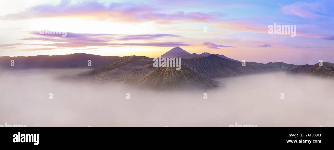 View from above, stunning panoramic view of the Mount Semeru, Mount bromo and the Mount Batok surrounded by clouds during a beautiful sunrise. Stock Photo
