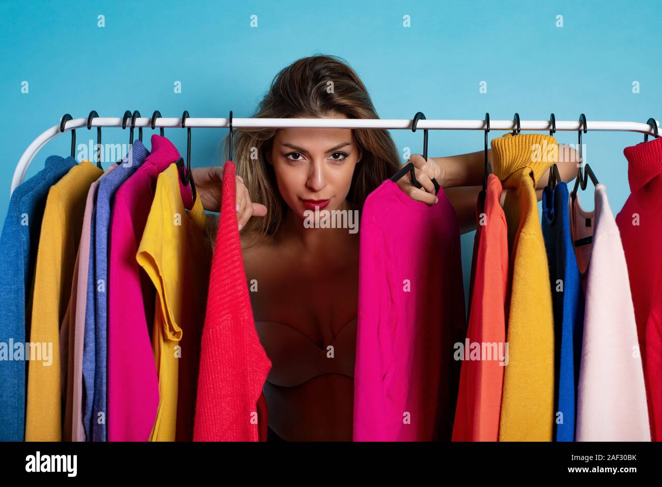 Blonde girl chooses the clothes to buy in a store. Concept of shopping and shopaholic Stock Photo