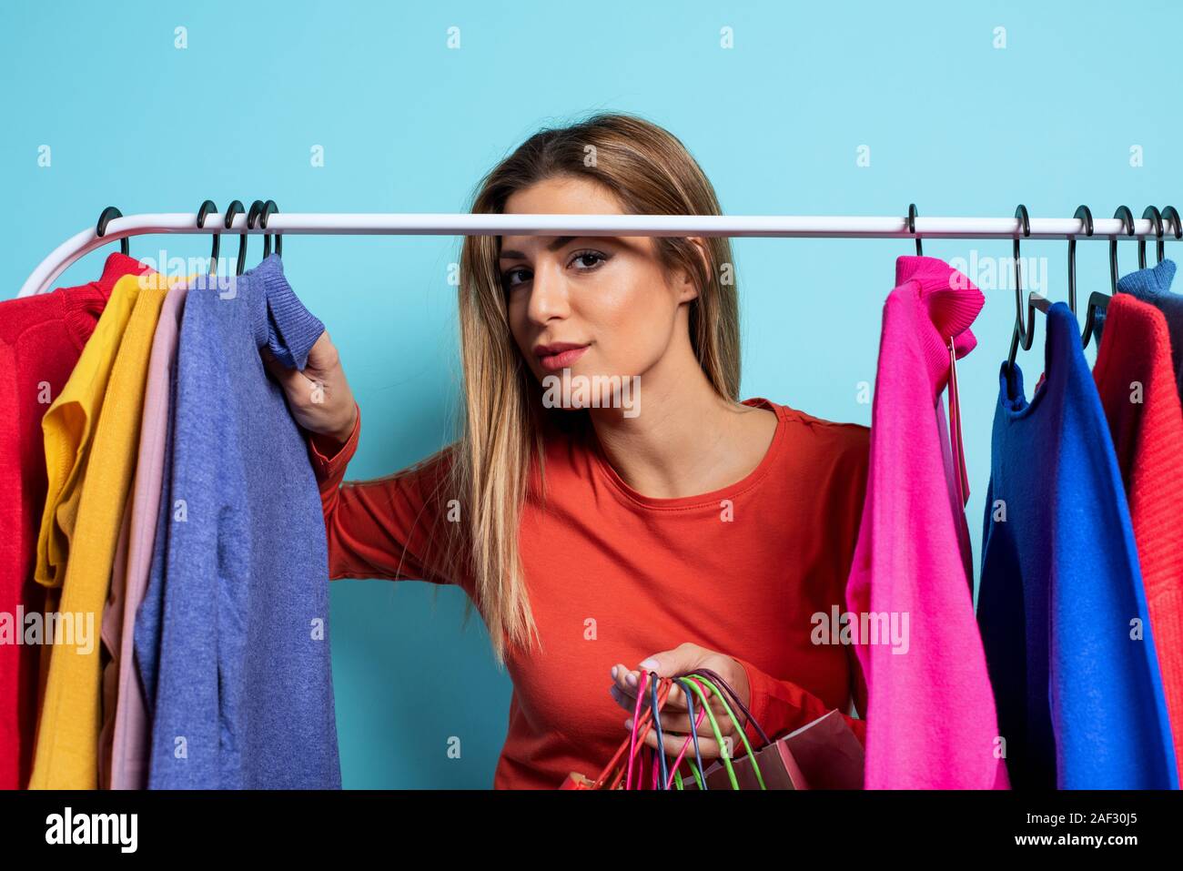 Blonde girl chooses the clothes to buy in a store. Concept of shopping and shopaholic Stock Photo