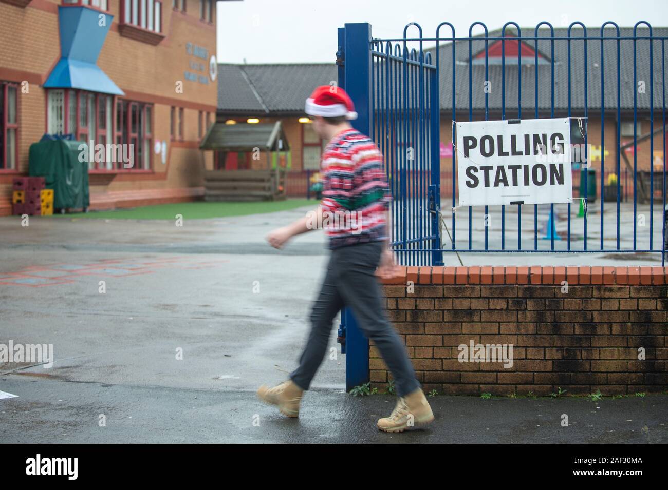 Stoke-on-Trent, UK. 12 December 2019. A voter takes a selfie outside a polling station while wearing a santa hat and christmas jumper in the rain. Stoke-on-Trent central is a key General Election battleground for both Labour and Conservatives. [EDITORIAL NOTE: Male shown in photograph did not provide name but consented to photo being used for editorial usage] Credit: Benjamin Wareing/ Alamy Live News Stock Photo