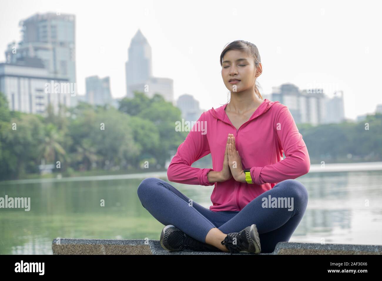 Asian young woman is practicing yoga at central city park. Stock Photo