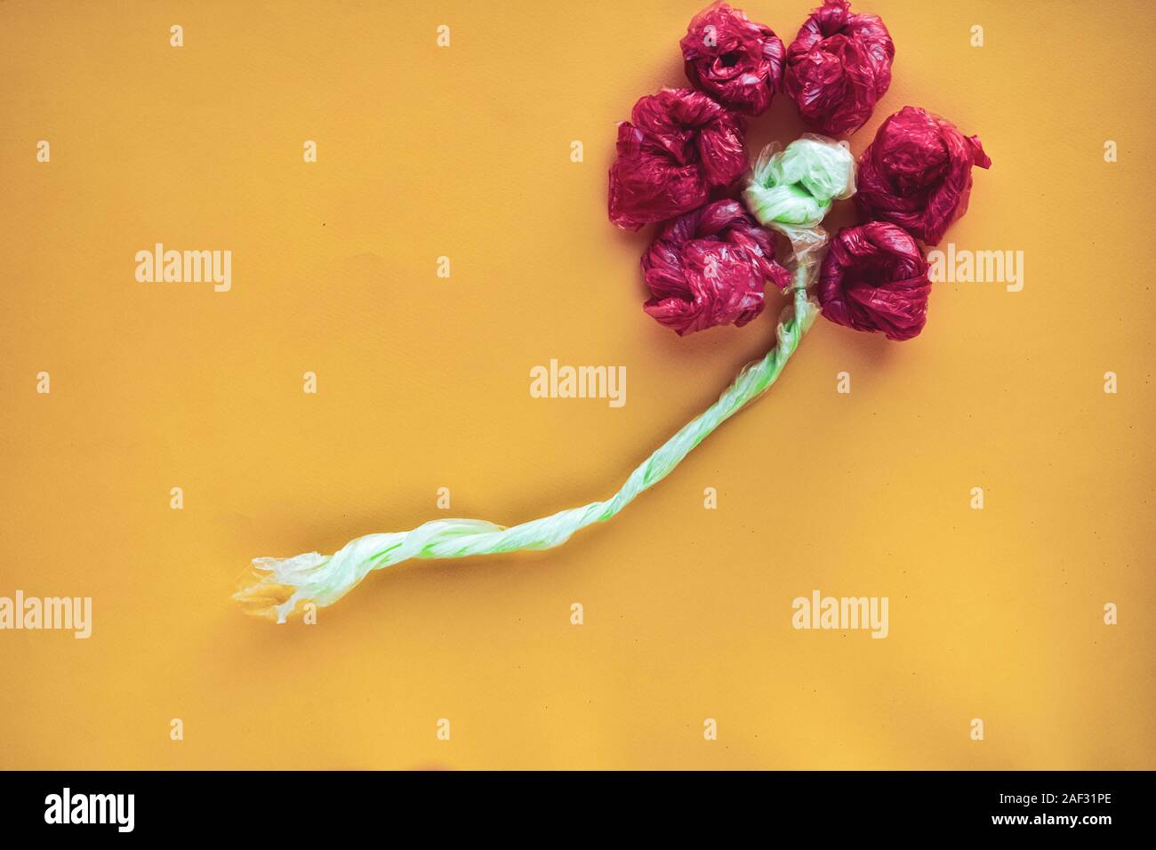 Flower made of rolled colorful plastic bags. Recycling and waste reducing concept. Top view. Stock Photo