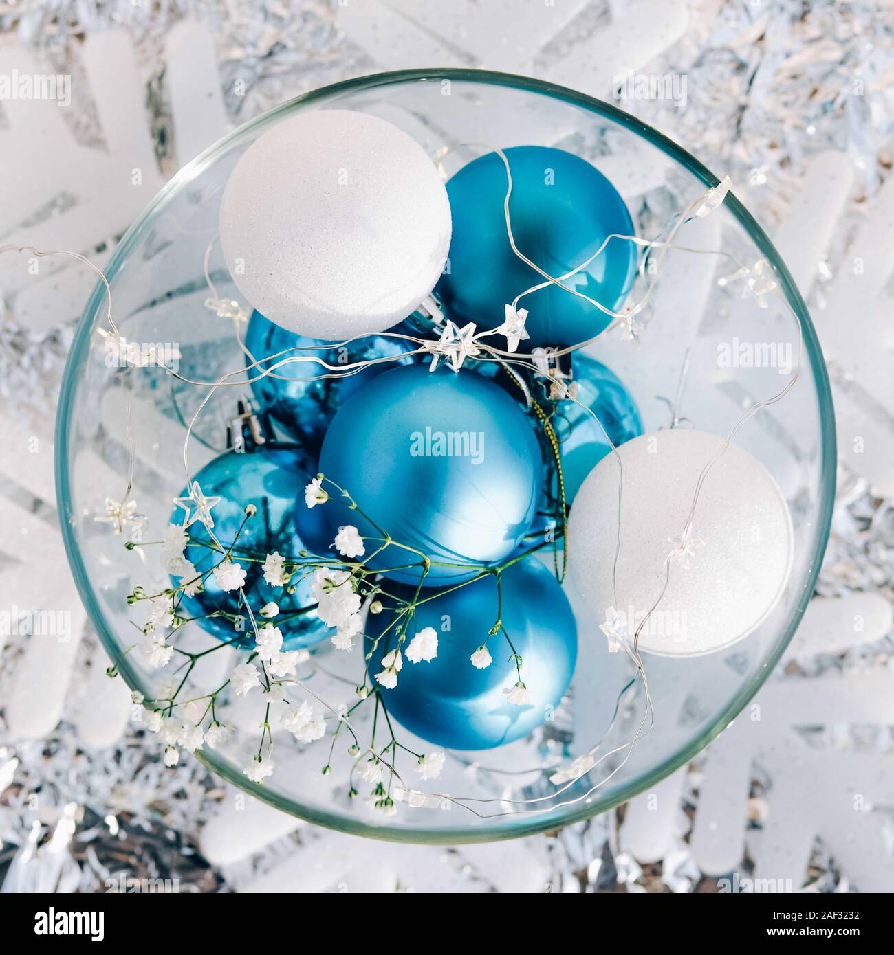 White and blue holiday decorations on silver background. Christmas balls, candle and fairy lights.Color of the year concept. Stock Photo