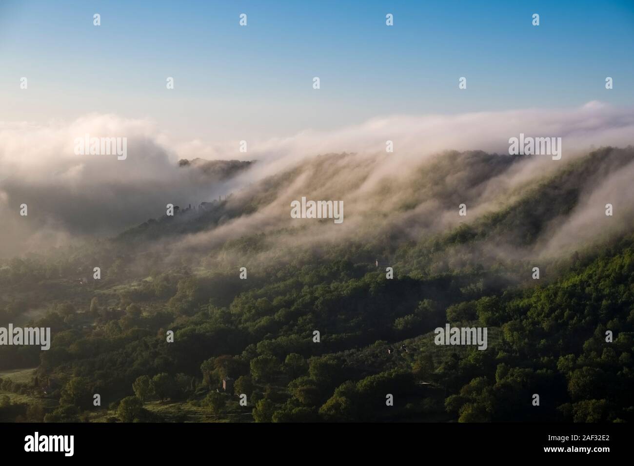 Wafts of mist flowing over a forested mountain ridge near Civita di Bagnoregio Stock Photo