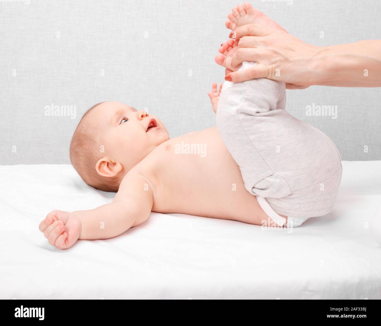 Happy six month baby girl receiving massage therapy in pediatric clinic. Manual therapist