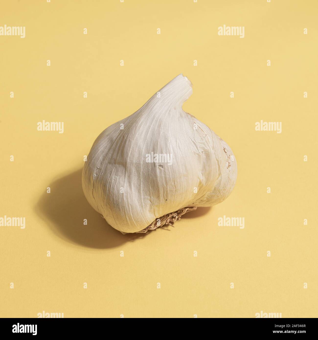 A garlic bulb on a yellow surface Stock Photo Alamy
