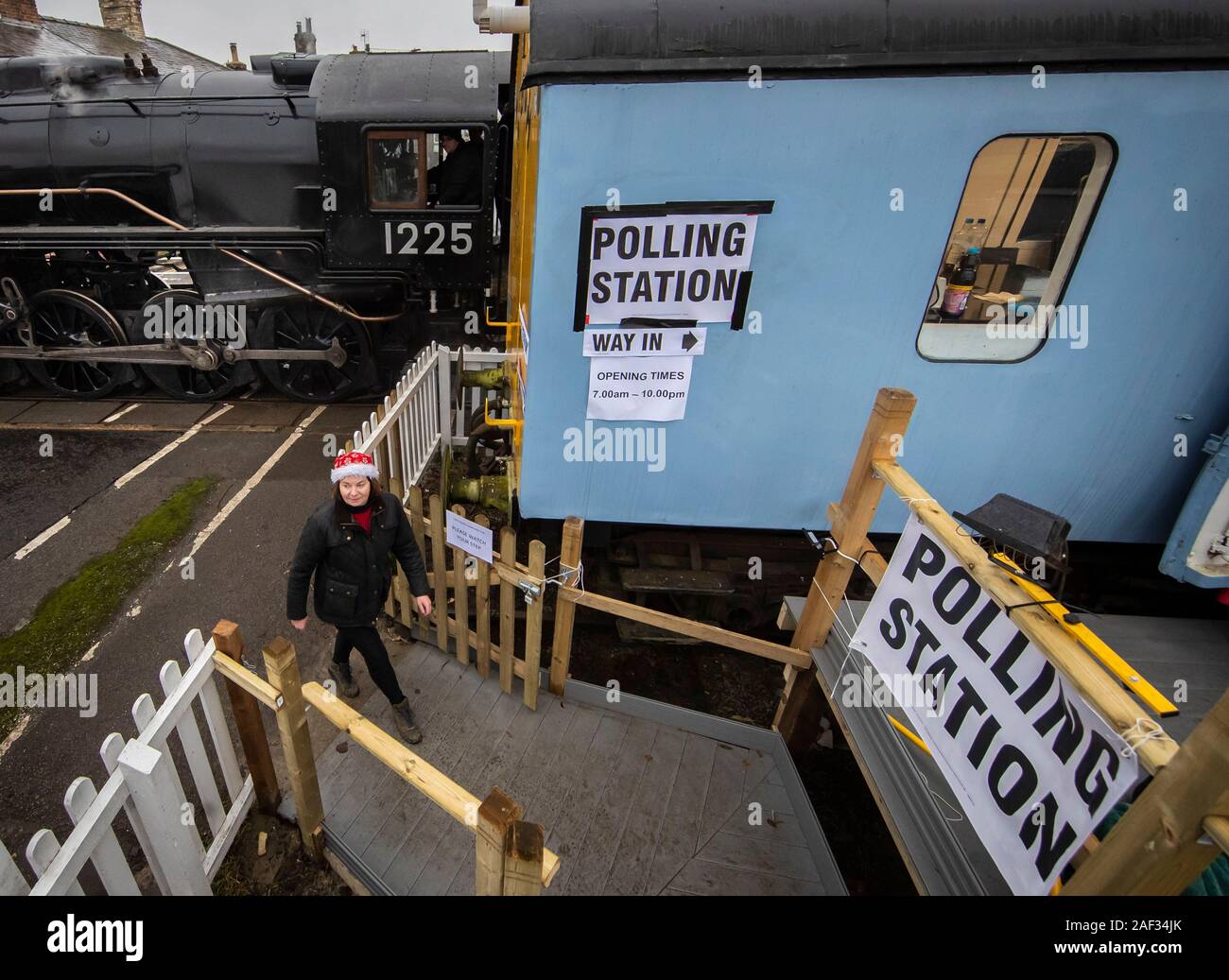 Wensleydale Railway employee Teresa Chapman is pictured with the Polar Express next to a polling station in a railway carriage in Leeming Bar, North Yorkshire, as voters go to the polls in what has been billed as the most important General Election in a generation. Stock Photo
