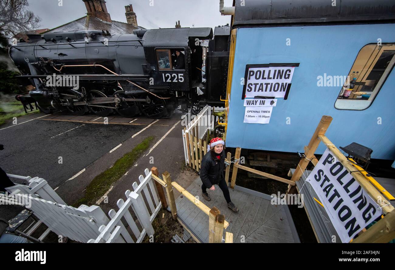 Wensleydale Railway employee Teresa Chapman is pictured with the Polar Express next to a polling station in a railway carriage in Leeming Bar, North Yorkshire, as voters go to the polls in what has been billed as the most important General Election in a generation. Stock Photo
