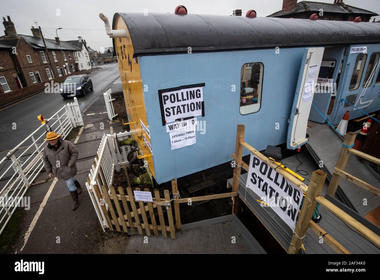 A woman walks past a polling station in a railway carriage in Leeming Bar, North Yorkshire, as voters go to the polls in what has been billed as the most important General Election in a generation. Stock Photo