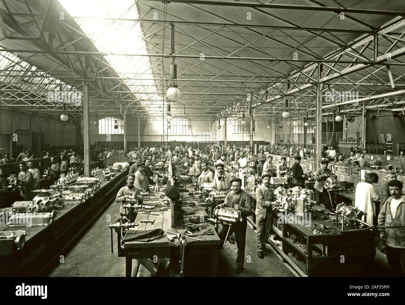 The production line at the Renault vehicle manufacturing plant at Boulogne-Billancourt, Paris, France c.1920, with workers assembling engines, crankshafts and gearboxes. Stock Photo