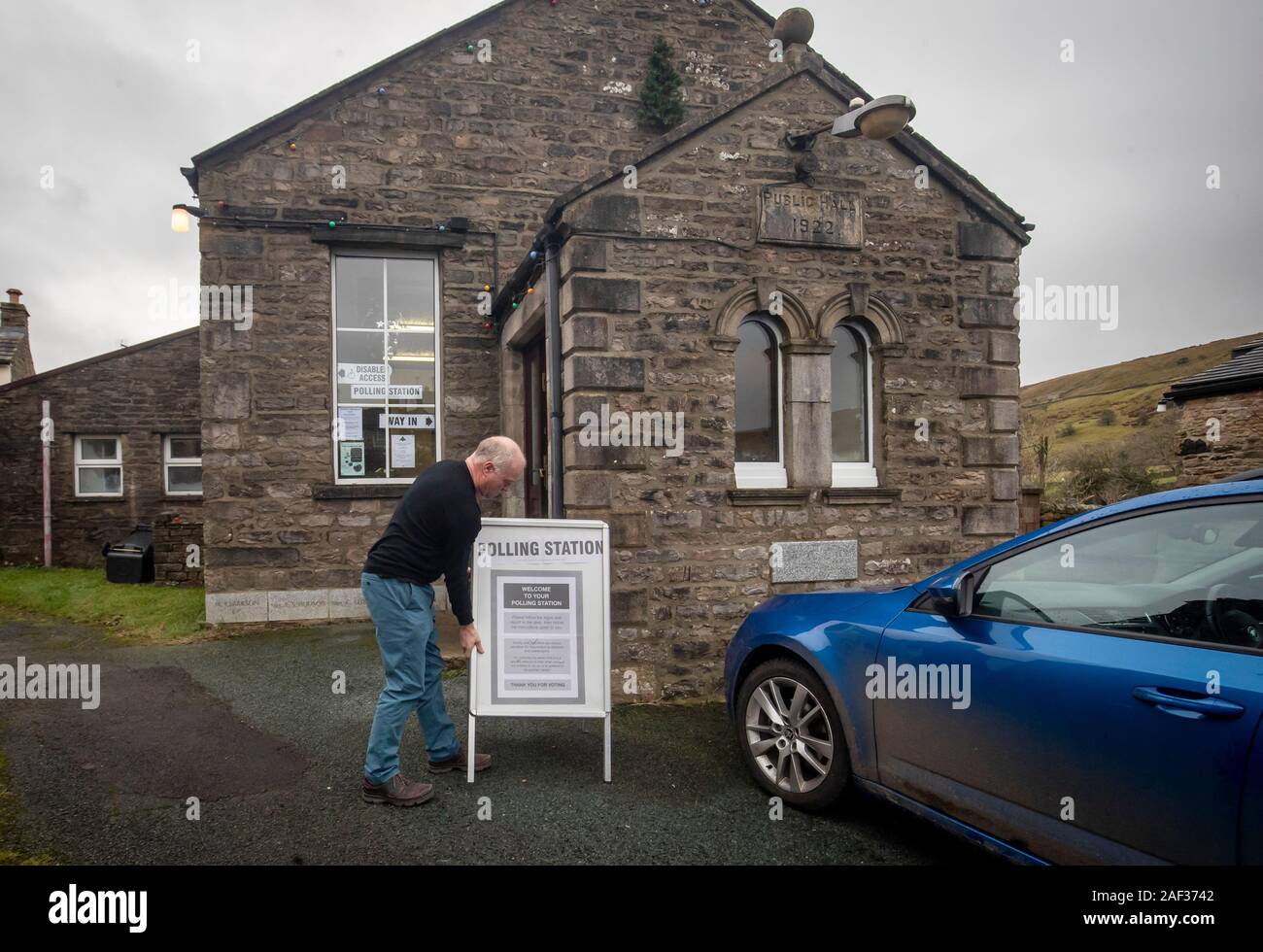 A man moves a polling station sign in Muker, Yorkshire, as voters go to the polls in what has been billed as the most important General Election in a generation. Stock Photo
