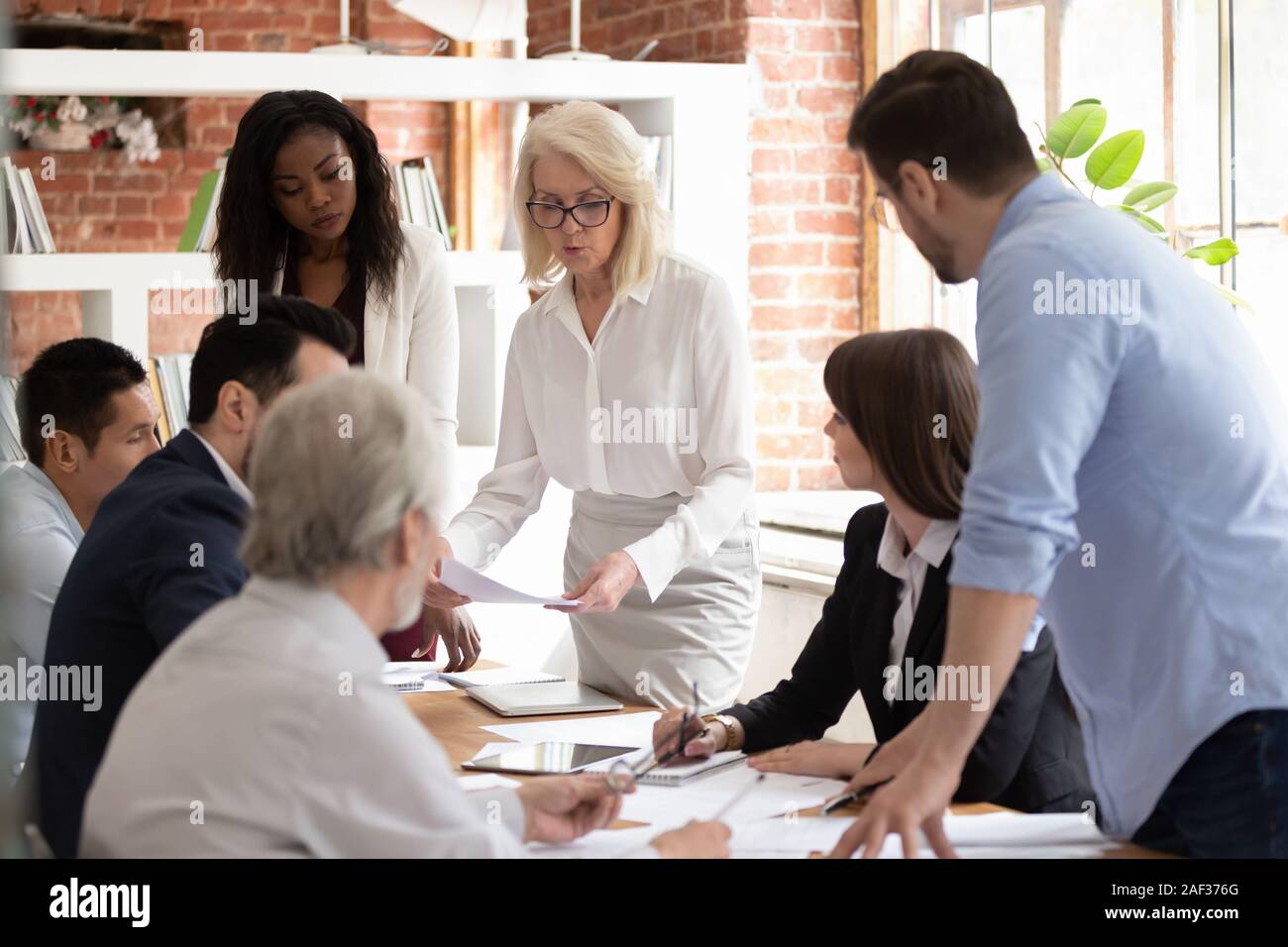 Diverse team and aged boss do paperwork analyzing financial report Stock Photo