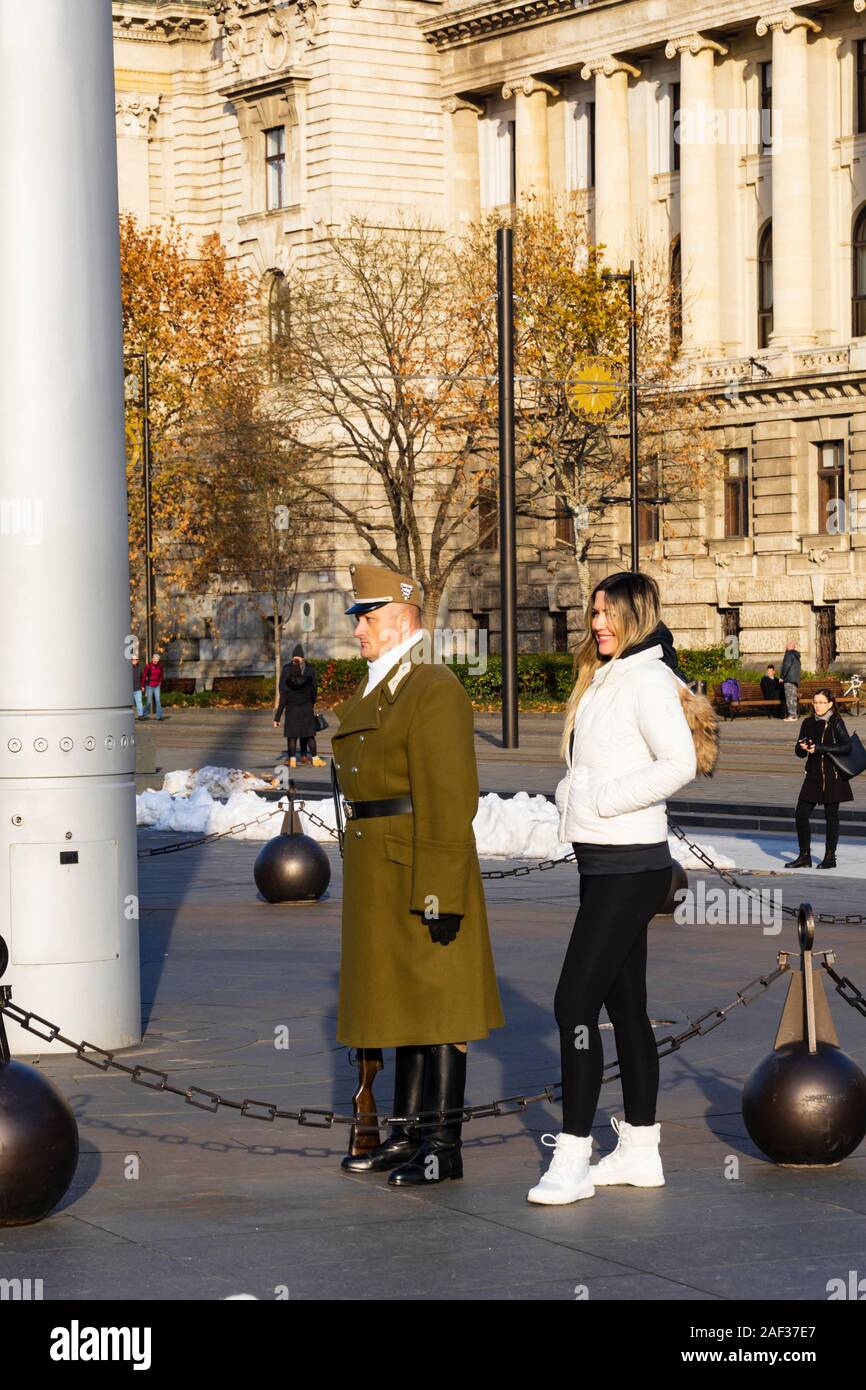 Hungarian female tourist poses with Army Guard at the Flag post outside the Parliament building, Orszaghaz,  in Kossuth Square, Winter in Budapest, Hu Stock Photo