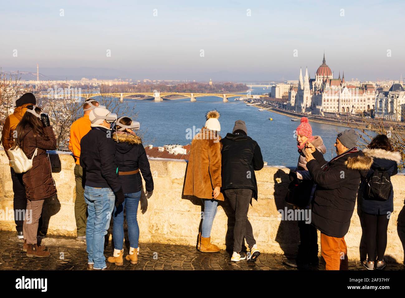 Tourists wearing virtual augmented  reality headsets look out from Buda Castle over the River Danube to the Hungarian Parliament building.Budapest, Hu Stock Photo