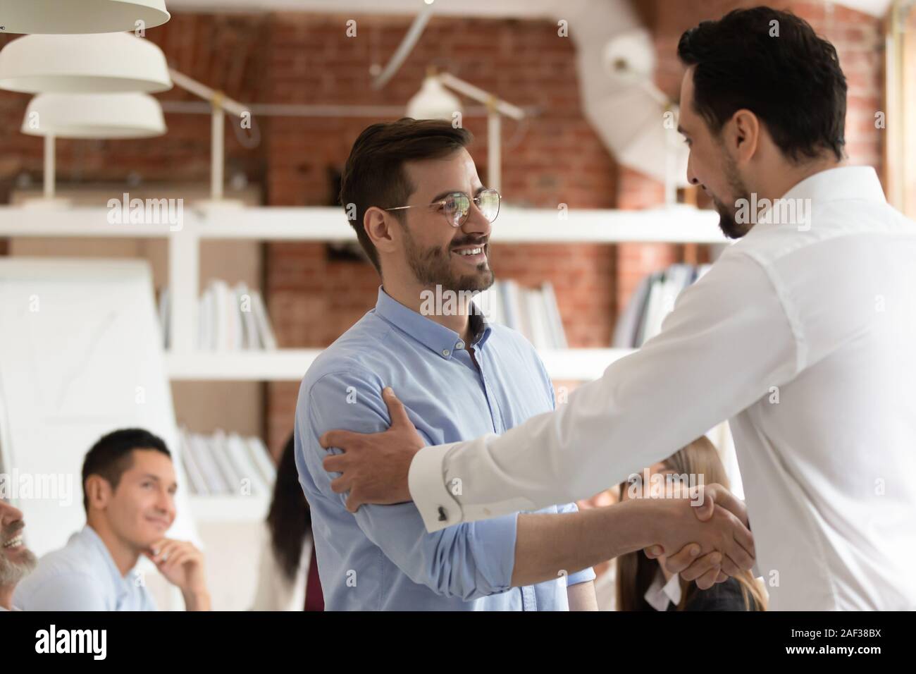 Middle east appearance boss praising employee express respect shaking hands Stock Photo