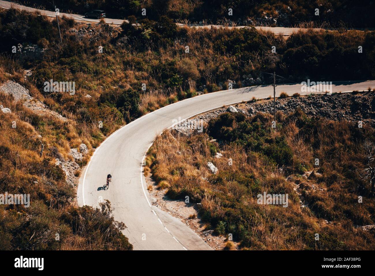 Small silhouette of rider on road bicycle, downhill on Sa Calobra, Mallorca Stock Photo