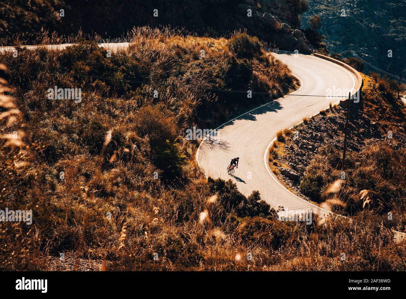 Small silhouette of rider on road bicycle, downhill on Sa Calobra, Mallorca Stock Photo