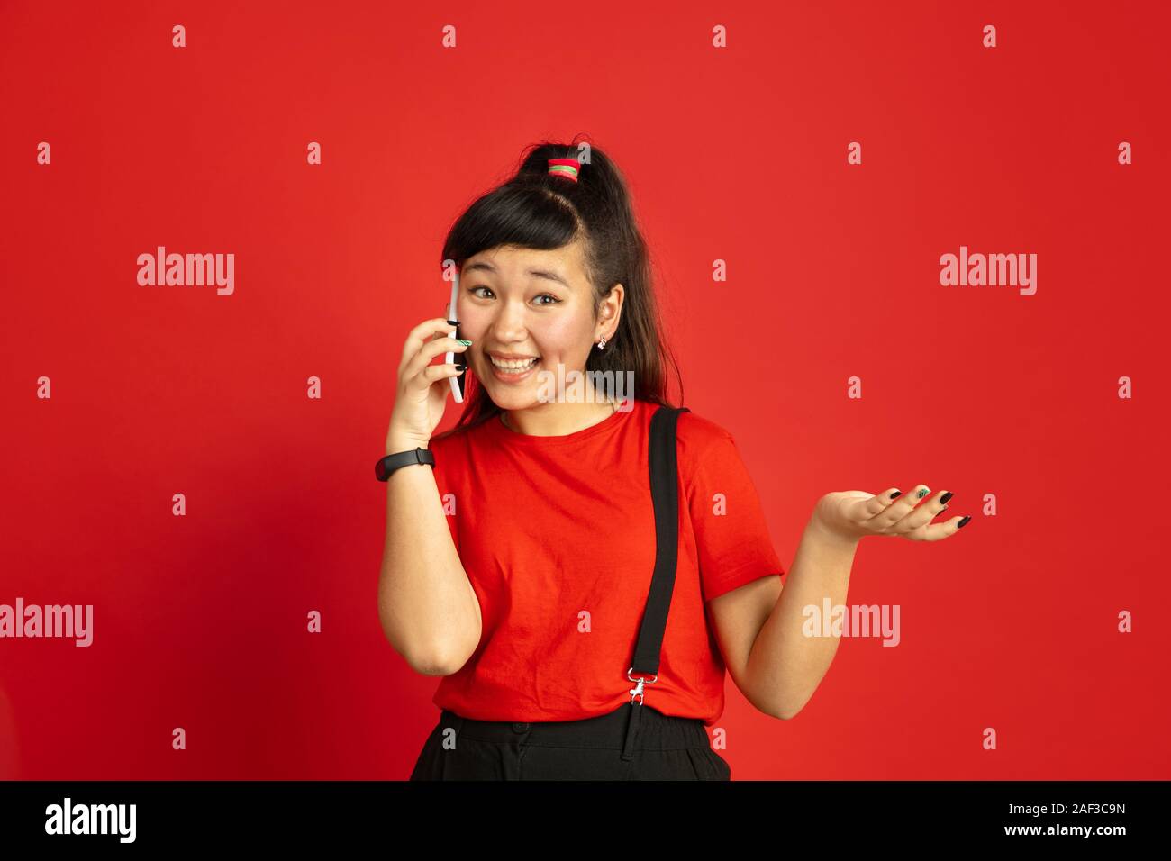 Asian teenager's portrait isolated on red studio background. Beautiful ...
