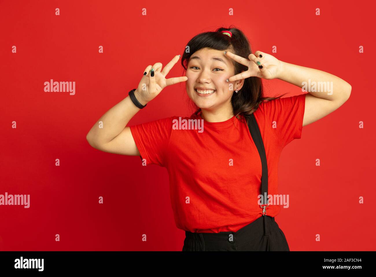 Asian teenager's portrait isolated on red studio background. Beautiful ...