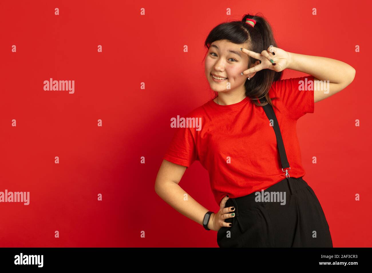 Asian teenager's portrait isolated on red studio background. Beautiful ...