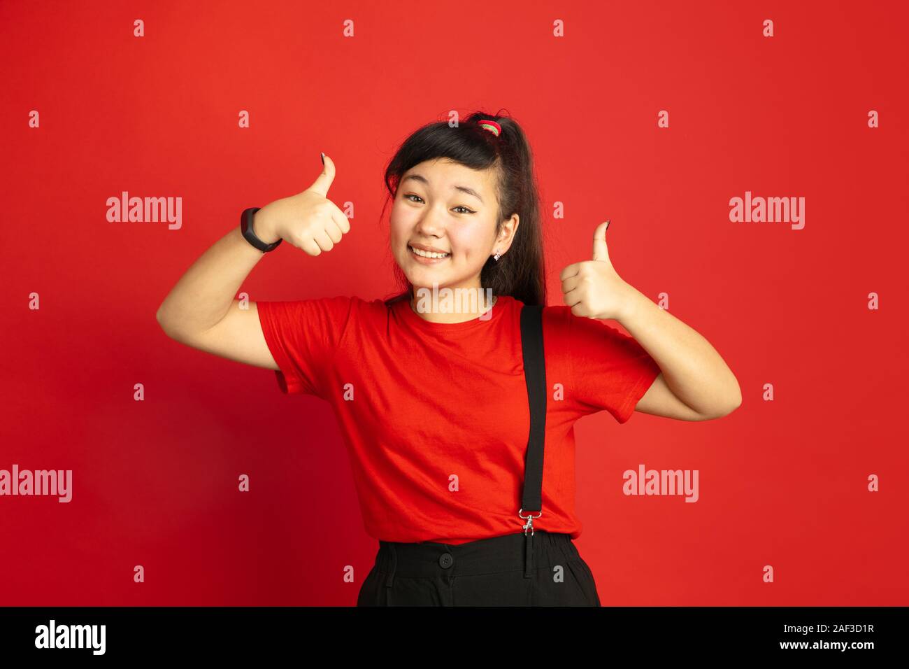 Asian teenager's portrait isolated on red studio background. Beautiful ...