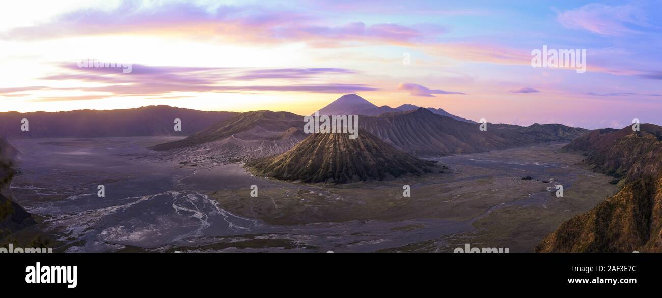 View from above, stunning panoramic view of the Mount Batok, Mount Bromo and the Mount Semeru in the distance illuminated at sunrise. Mount Bromo is a Stock Photo