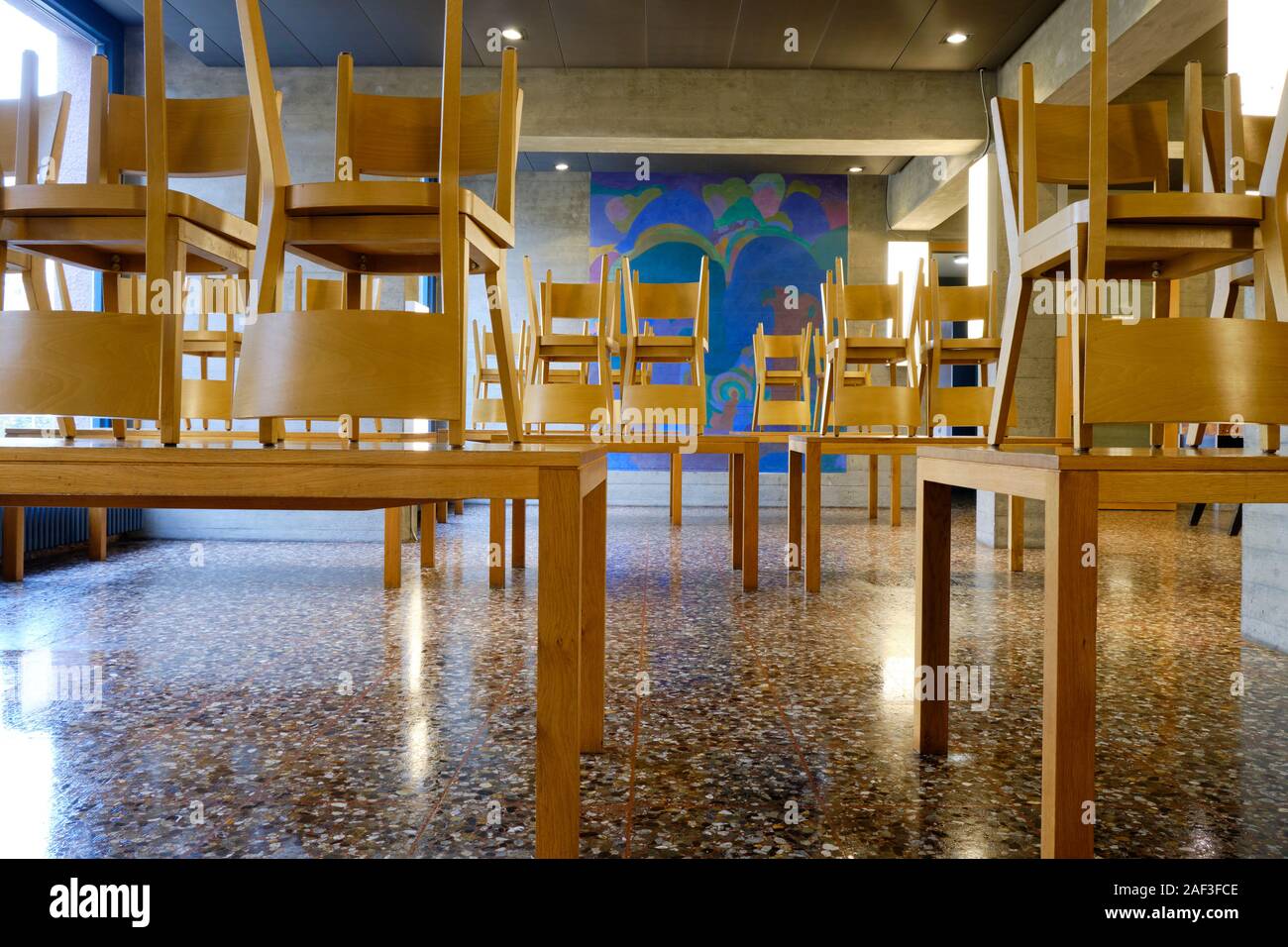 School type cafeteria eating area with all chairs raised on tables for floor cleaning Stock Photo