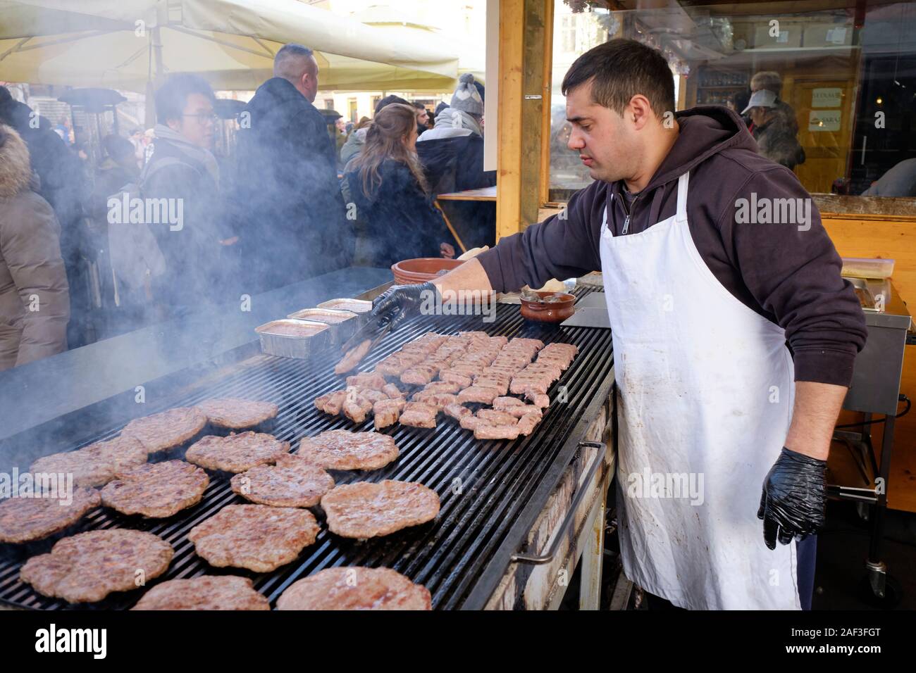 Man grilling cevapi and pljeskavica meat on outdoor grill at a winter food  festival Stock Photo - Alamy