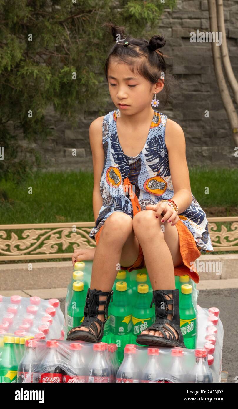 young girl sitting on drinks truck outside Forbidden City, Beijing, China Stock Photo