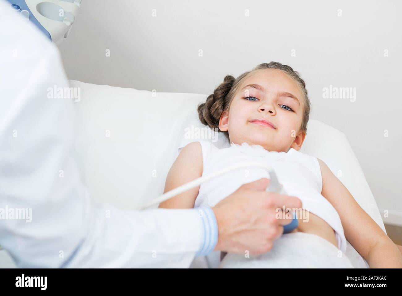 Sonographer moving transducer on belly of little girl. Modern clinical