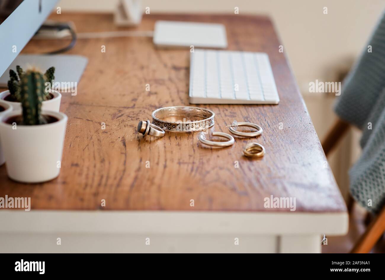 Woman's silver jewellery on a desk next to a computer Stock Photo