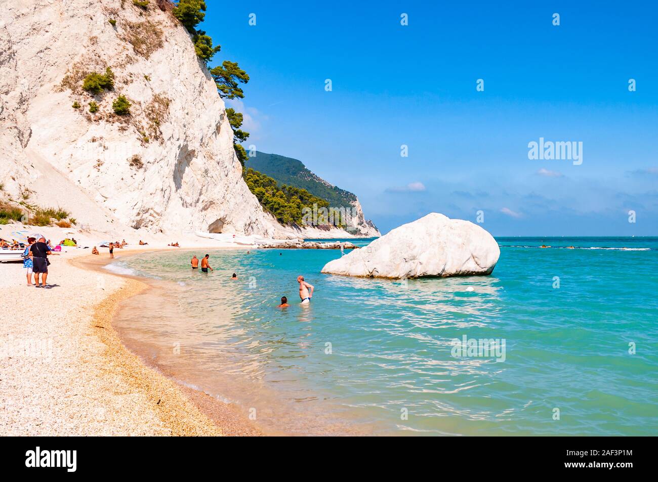 Spiaggia del Frate, Numana, Ancona, Marche, Italy - September 11, 2019: People resting on amazing white pebbles beach surrounded by high massive white Stock Photo