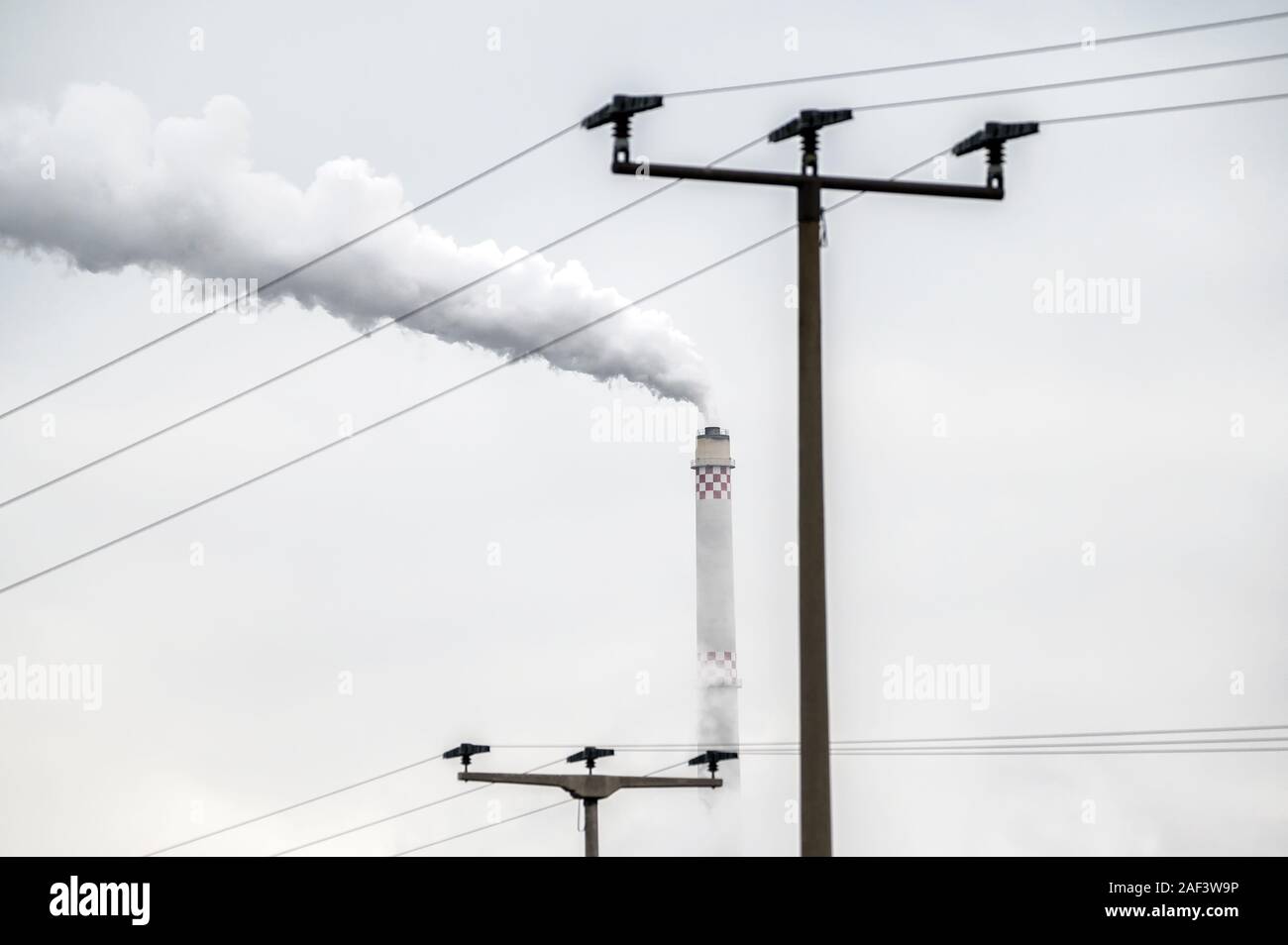 Electricity pylon and smoldering chimney as a symbol for dirty electricity from coal power plant Stock Photo