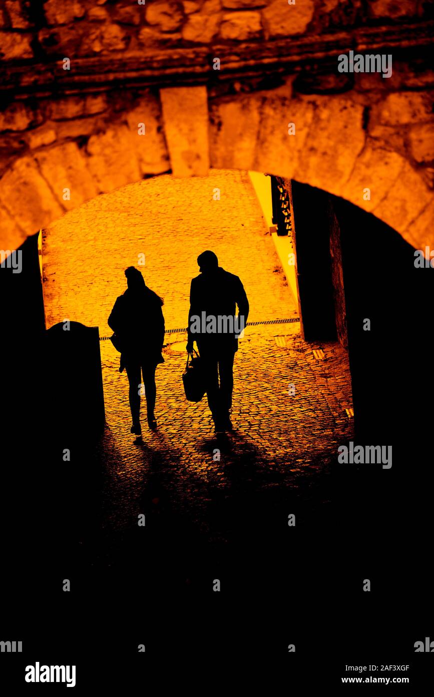Silhouette of a man and woman walking through an tunnel like passage Stock Photo