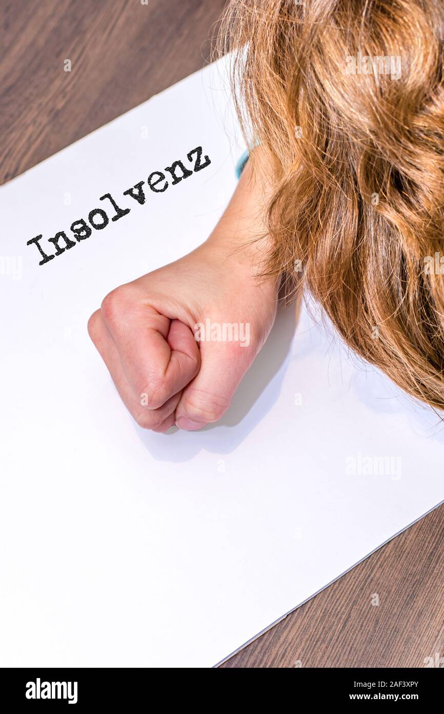 Desperate woman with a piece of paper on which the german word insolvency stands Stock Photo