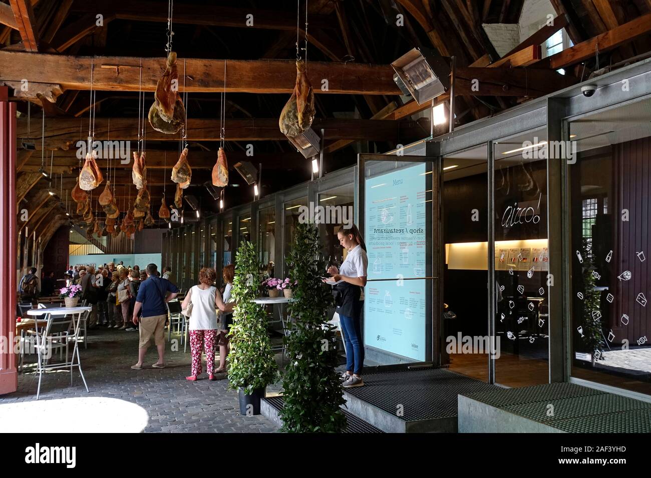 Tourists visiting the Groot Vleeshuis / Big Butchery with hams hanging from the ceiling in the city Ghent / Gent, East Flanders, Belgium Stock Photo