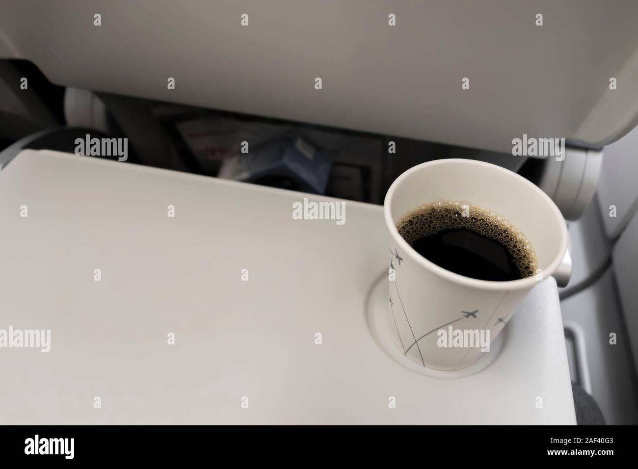 Coffee mug with black coffee in the plane on a folding table. Eating and drinking on the plane. Stock Photo