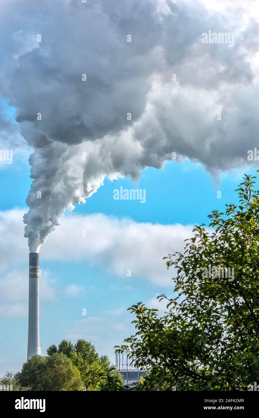 Huge cloud of smoke from a chimney over an industrial plant Stock Photo