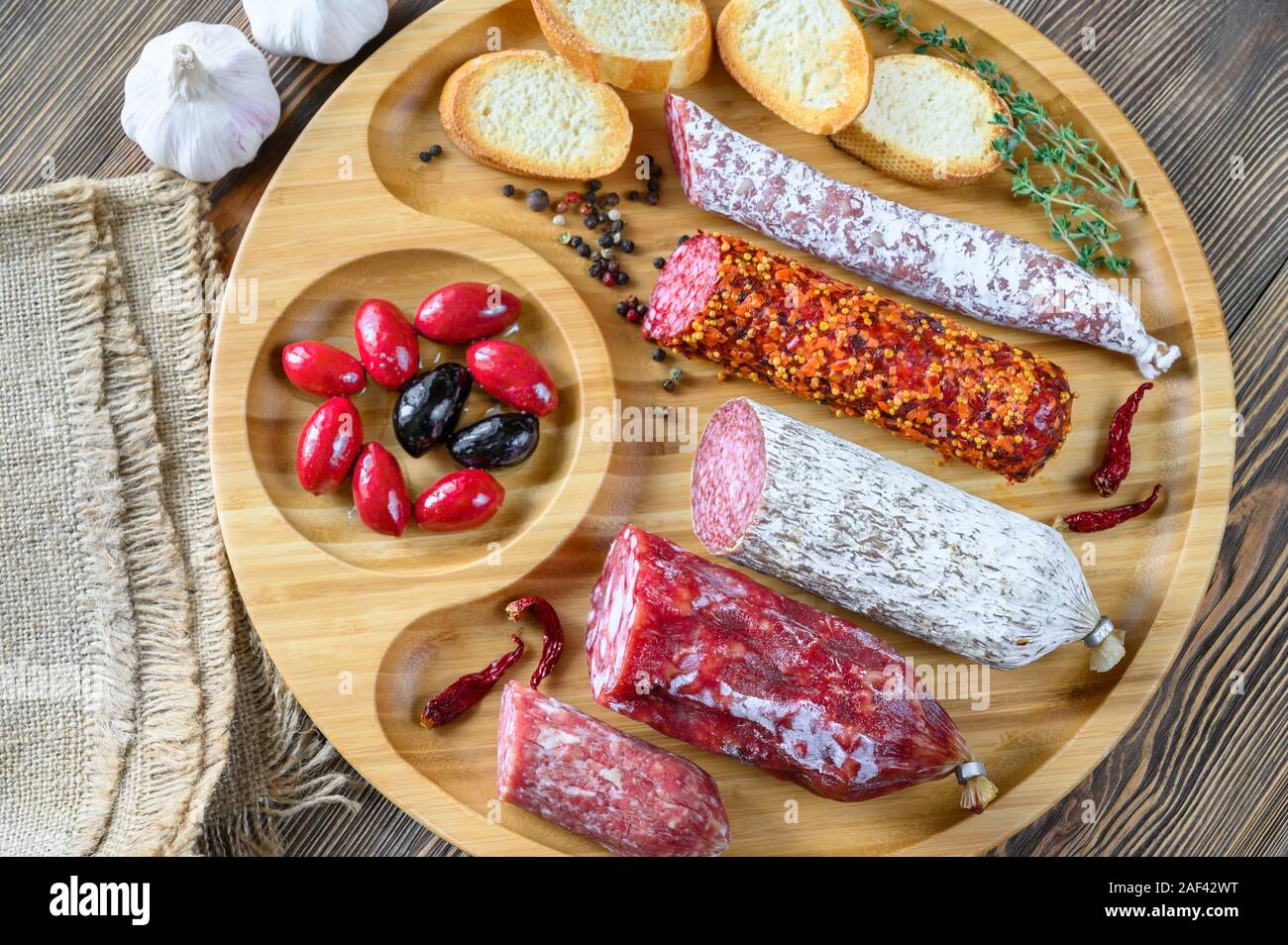 Assortment of salami with appetizers on wooden background top view