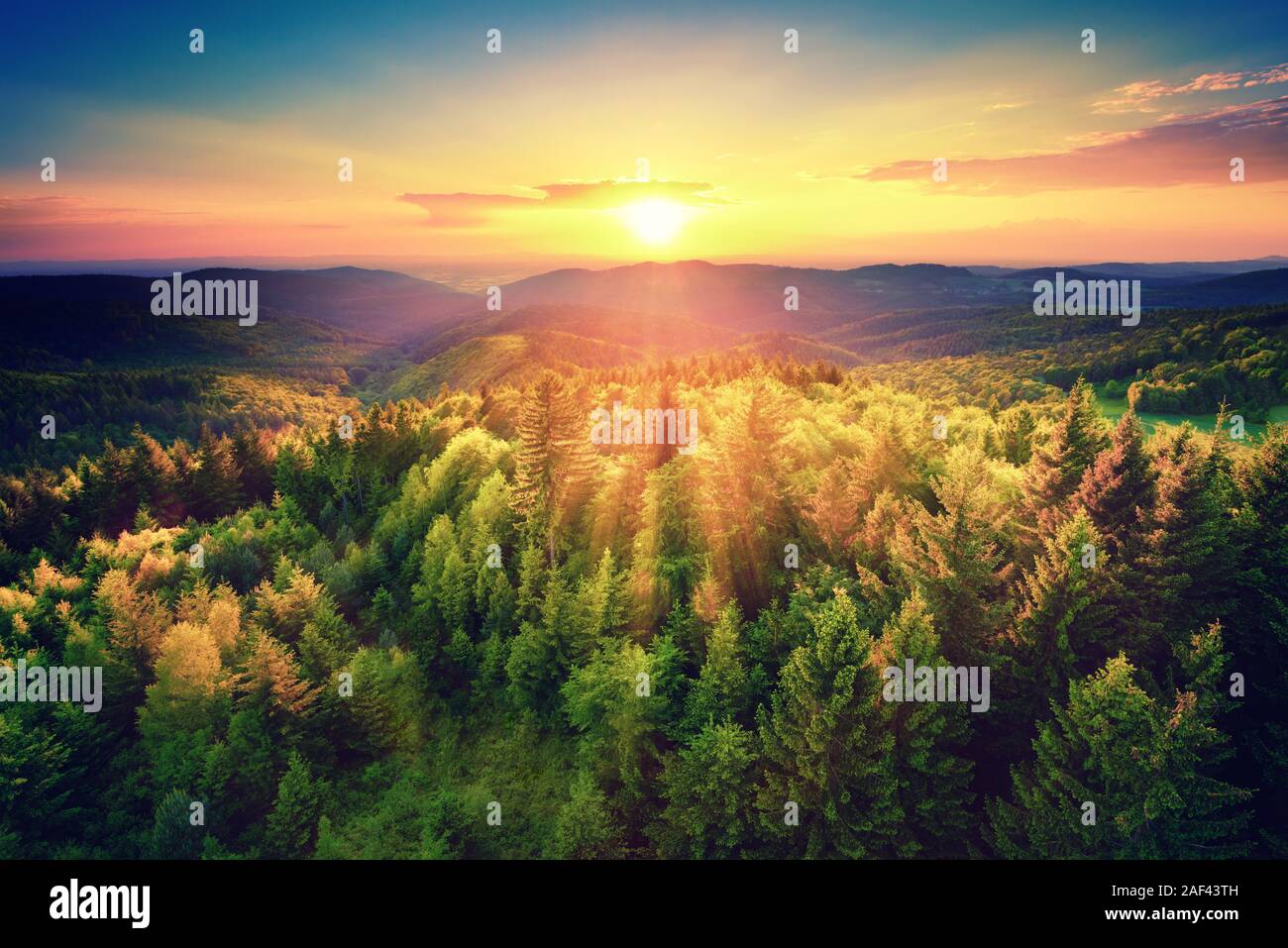 Bird's-eye view of a scenic sunset over the   forest hills, with toned dramatic colors Stock Photo