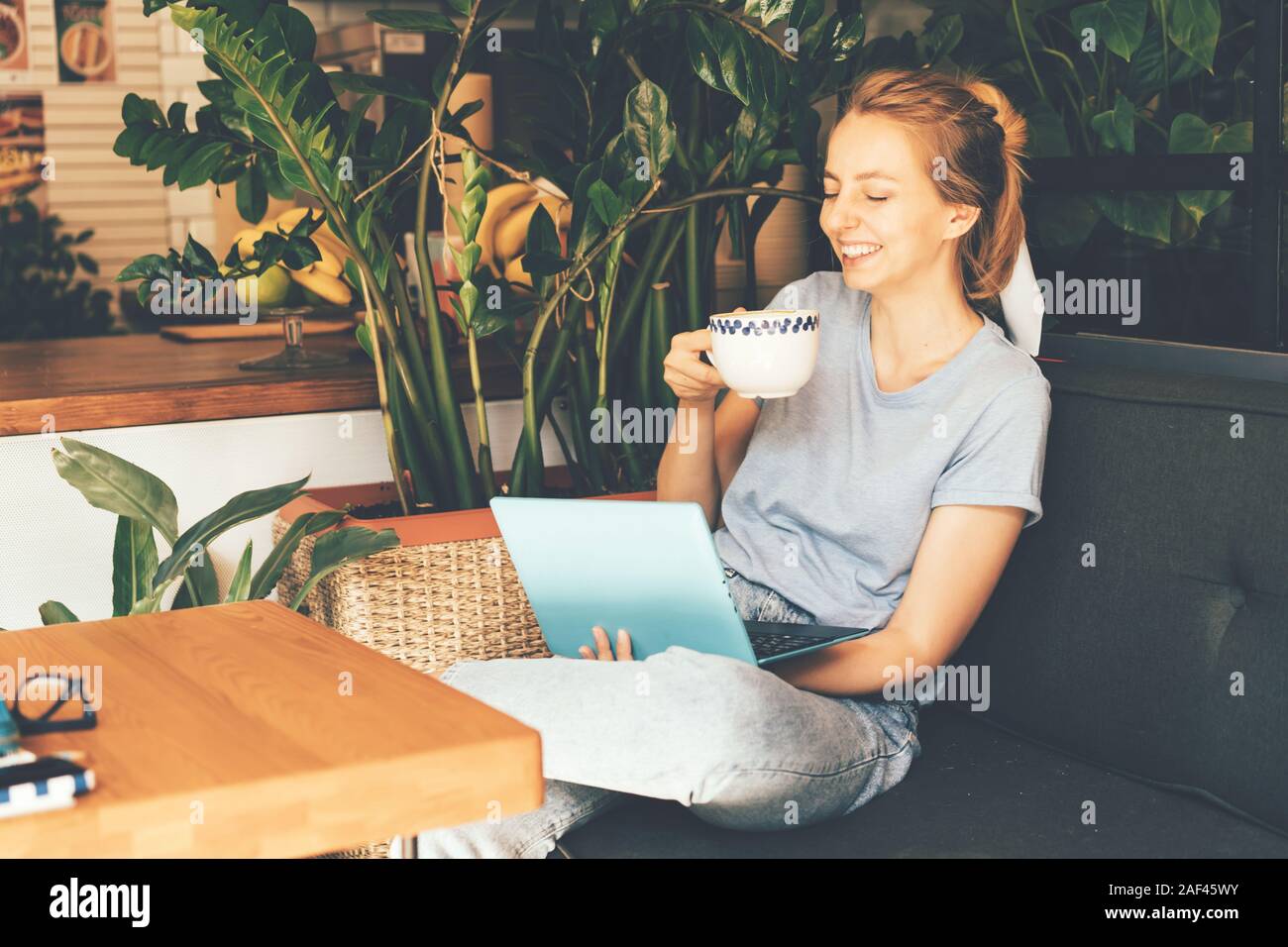 girl with a laptop drinks a drink and laughs Stock Photo