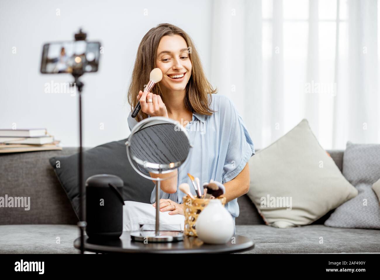 Young woman recording on a smart phone her vlog about cosmetics, showing and demonstrating makeup. Influencer marketing in social media concept Stock Photo