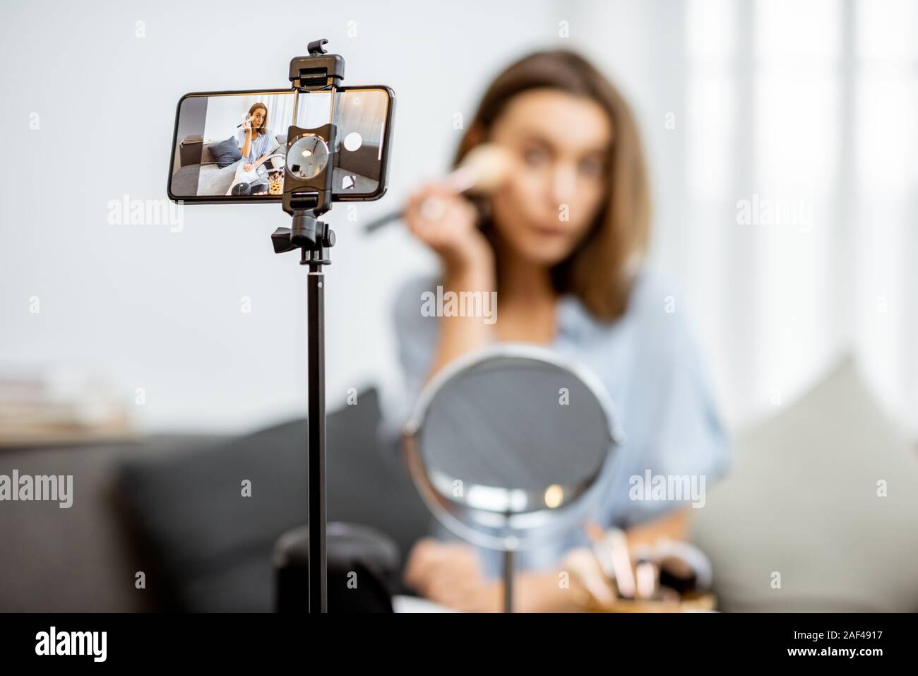 Young woman recording on a smart phone her vlog about cosmetics, showing and demonstrating makeup. Influencer marketing in social media concept Stock Photo