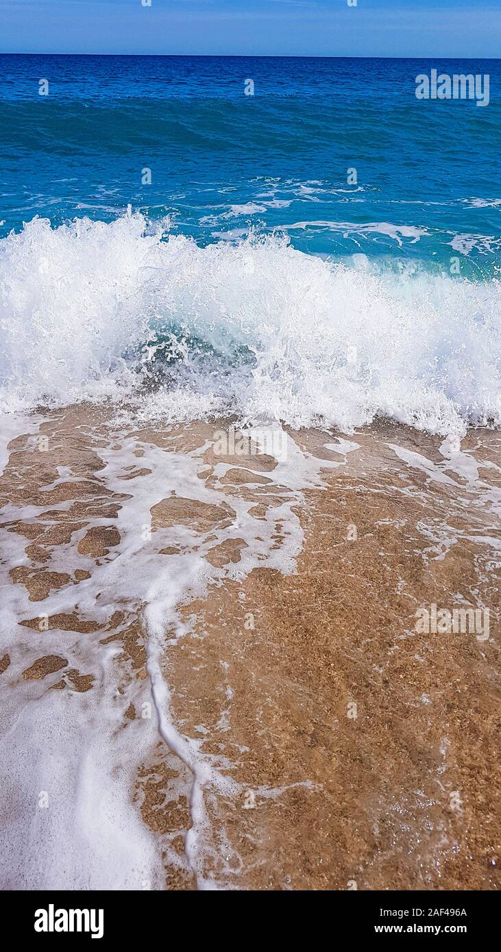 abstract background of sea waves, on golden sand, white sea foam. Stock Photo