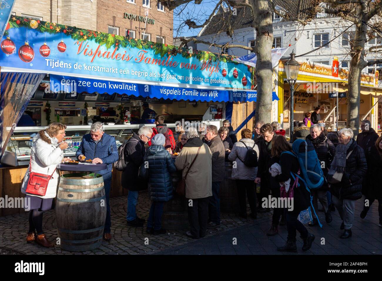 People enjoying fresh fried Kibbeling fish at the christmas market on the vrijthof in Maastricht Stock Photo